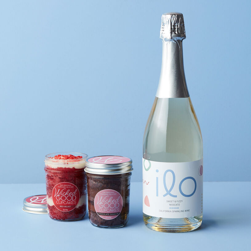 This gift features Wicked Good Cupcakes Chocolate Ganache and Red Velvet Cupcake Jars paired with Ilo Moscato California Sparkling Wine.