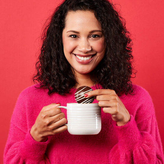 Model holding mug with hot cocoa bomb