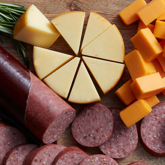 Alternate view of Hickory Farms smoked gouda cheese on a charcuterie board with beef summer sausage and farmhouse cheddar cheese