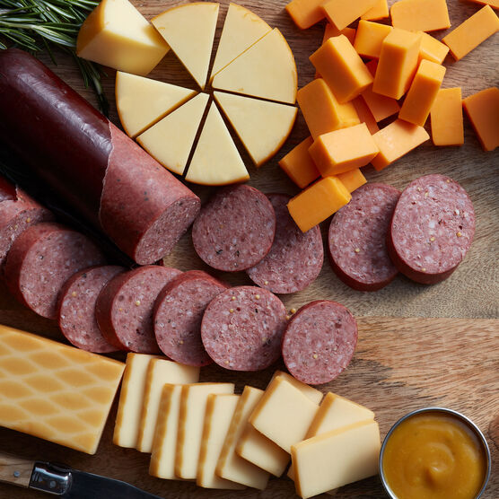 Alternate view of Hickory Farms smoked cheddar cheese on a charcuterie board with beef summer sausage and farmhouse cheddar cheese