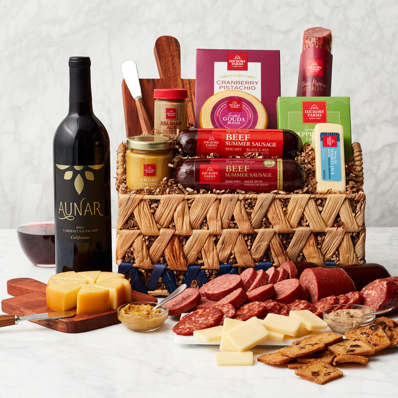 This basket is filled with savory salami, cheeses, mustard, chutney, tapenade, crackers, cheese board and spreader, and a bottle of wine