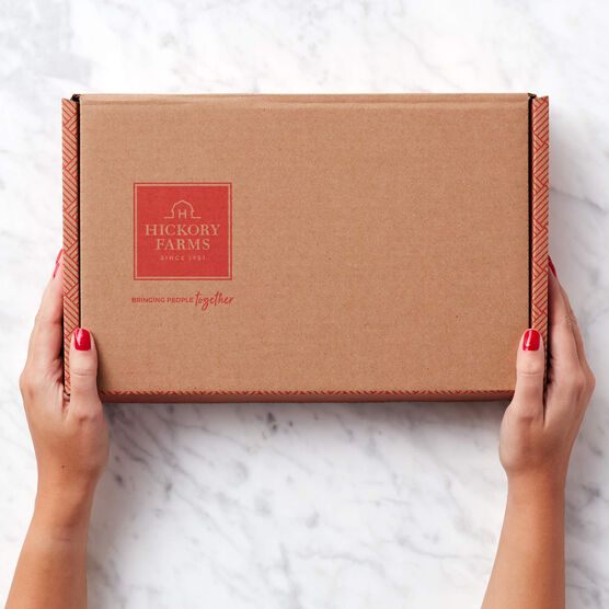 Hands holding Hickory Farms mailer box on marble background