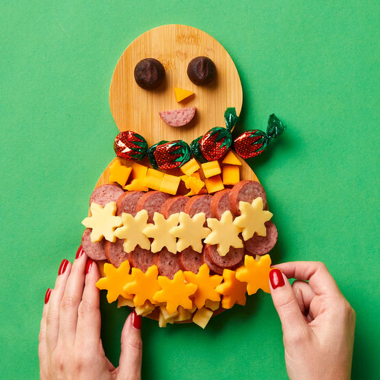 Hickory Farms Mini Snowman Charcuterie Board with hands taking a piece of cheese