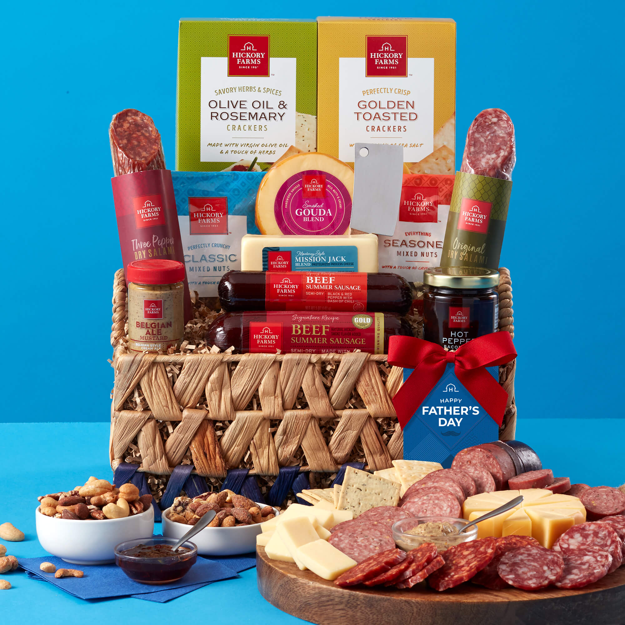 A gift basket filled with summer sausage, cheese, snacks, and sweets on a blue background