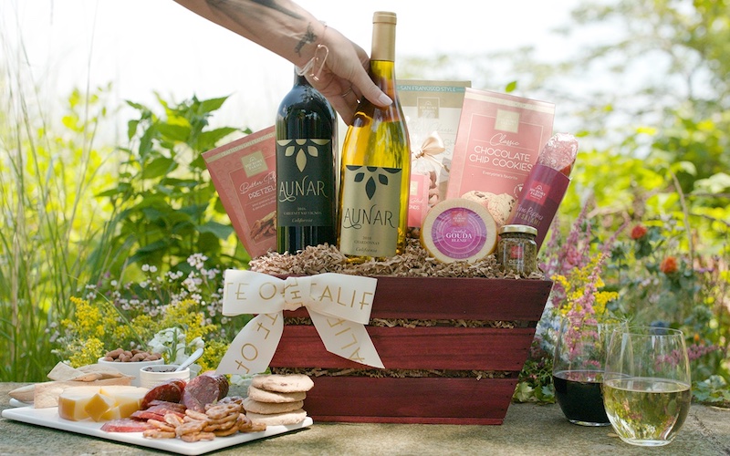 Image of wine in a wicker basket with wrapped gifts in front of a photo backdrop