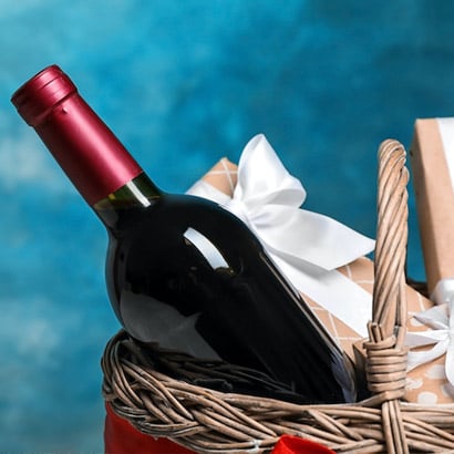 red wine bottle in basket with blue background