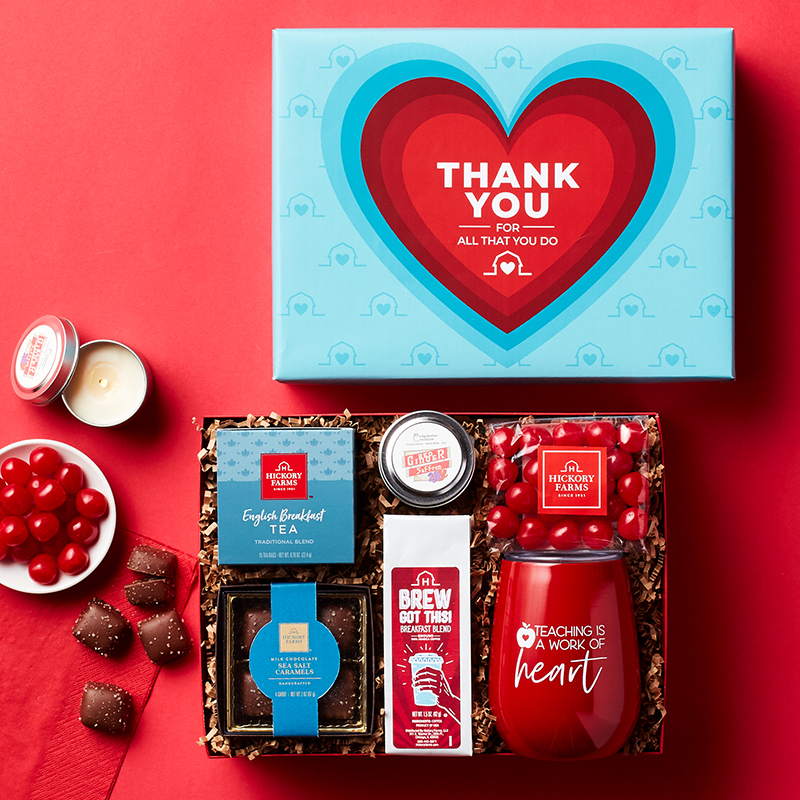 A photo of an opened thank you gift for teachers, featuring a motivational tumbler, tea, coffee, and sweets.