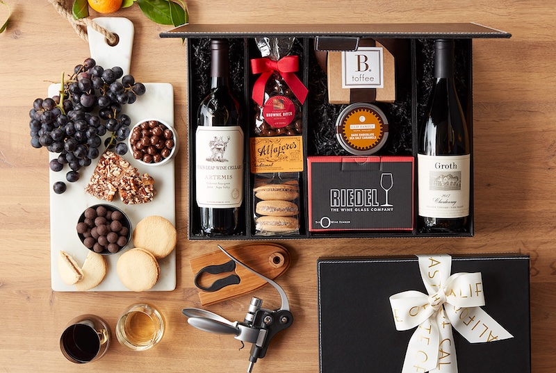 Picture of marble cheese board with popular fruit and sweet pairings, a wine gift box, and wine accessories like a bottle opener