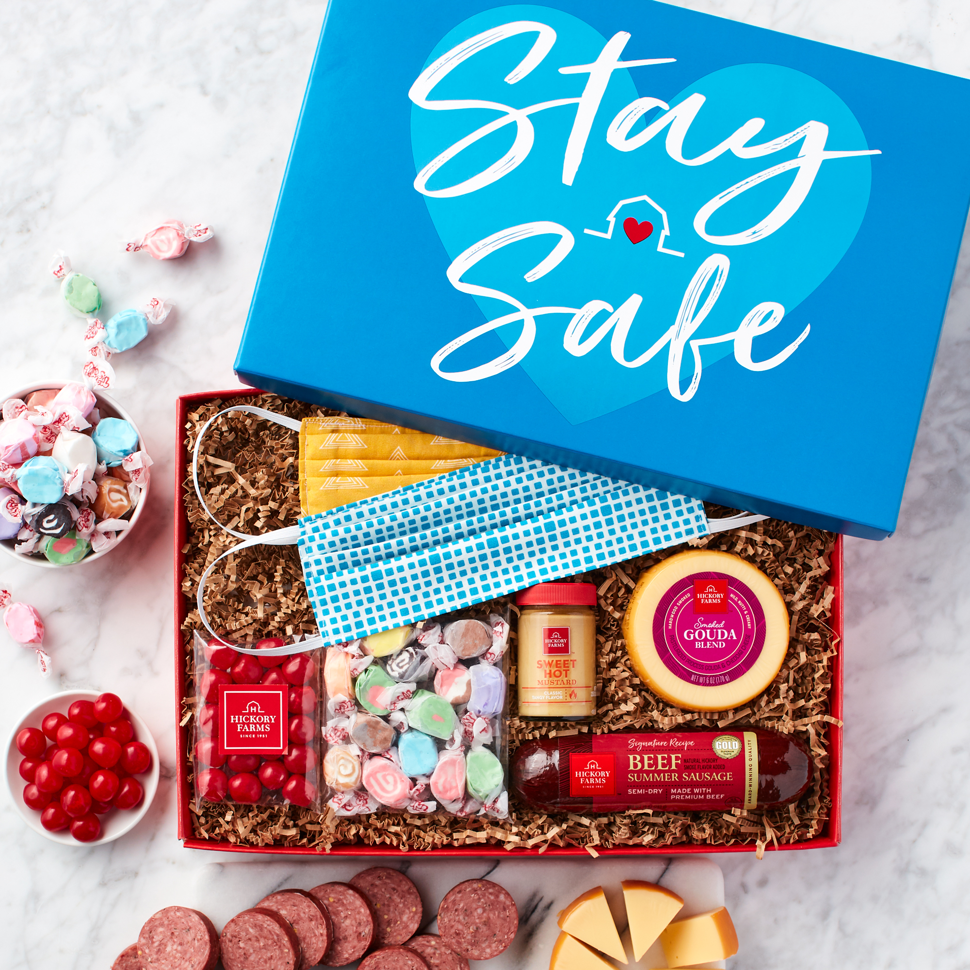 This quarantine gift box features Beef Summer Sausage, Gouda, Sweet Hot Mustard, Cherry Sours, Taffy and two handcrafted face masks.