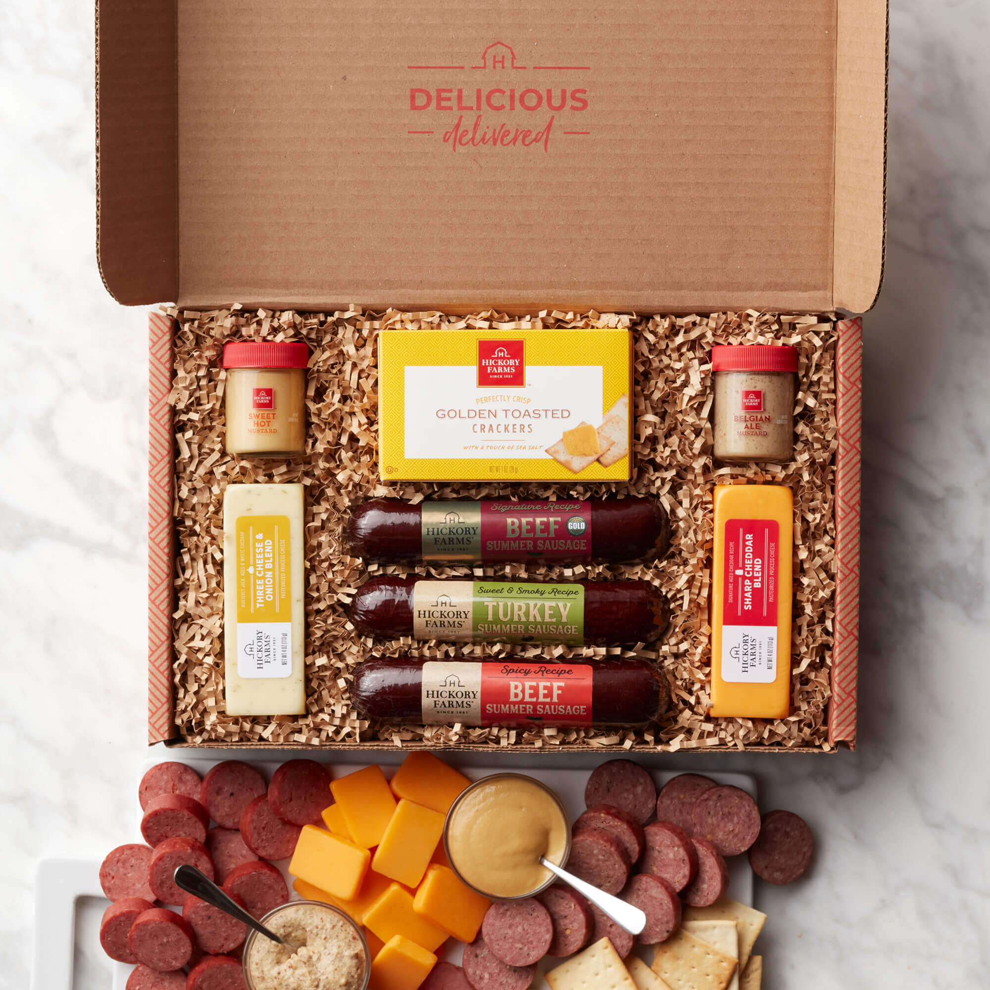 The Hearty Bites Gift Box includes beef, turkey, and spicy sausage, crackers, and various mustards and cheeses